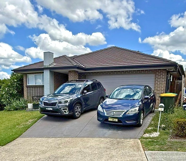 Before Second storey Addition Mount Annan 60m2 Before photo of a single-storey brick home in Mount Annan prior to a 60m² second storey addition, showing the existing house façade, tiled roof and double garage.